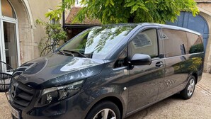 A black van parked on a gravel driveway.