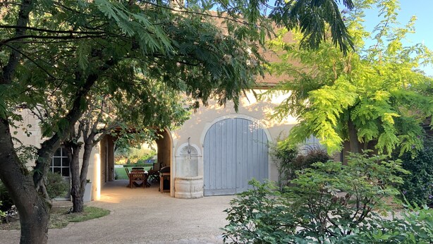 A gravel pathway leading to a building with a large arched entrance and a door.