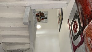 A staircase with white painted railings leading to a room with a large abstract painting and a small decorative item on the wall.