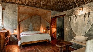 A rustic bedroom with a wooden bed, a wooden nightstand, a wooden bench, and a woven canopy bed. - Aldea Colibrí (Tulum)
