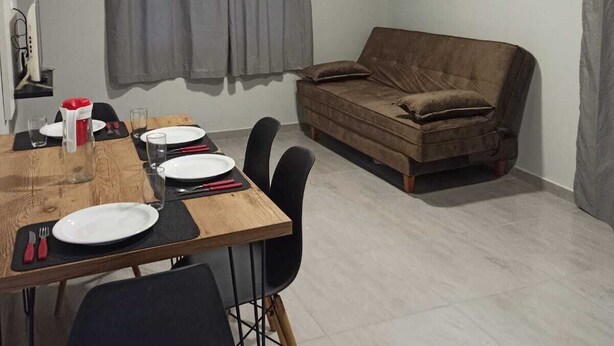 A dining area with a wooden table set for four, a brown sofa, and a framed picture on the wall. - Leandro's Residence. Casa em Balneário Camboriú Para Aproveitar com a Família! (Balneário Camboriú)