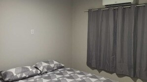 A bedroom with a bed, an air conditioning unit, and a curtain. - Leandro's Residence. Casa em Balneário Camboriú Para Aproveitar com a Família! (Balneário Camboriú)