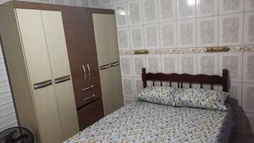 Ein Schlafzimmer mit Bett, Kleiderschrank und Ventilator.