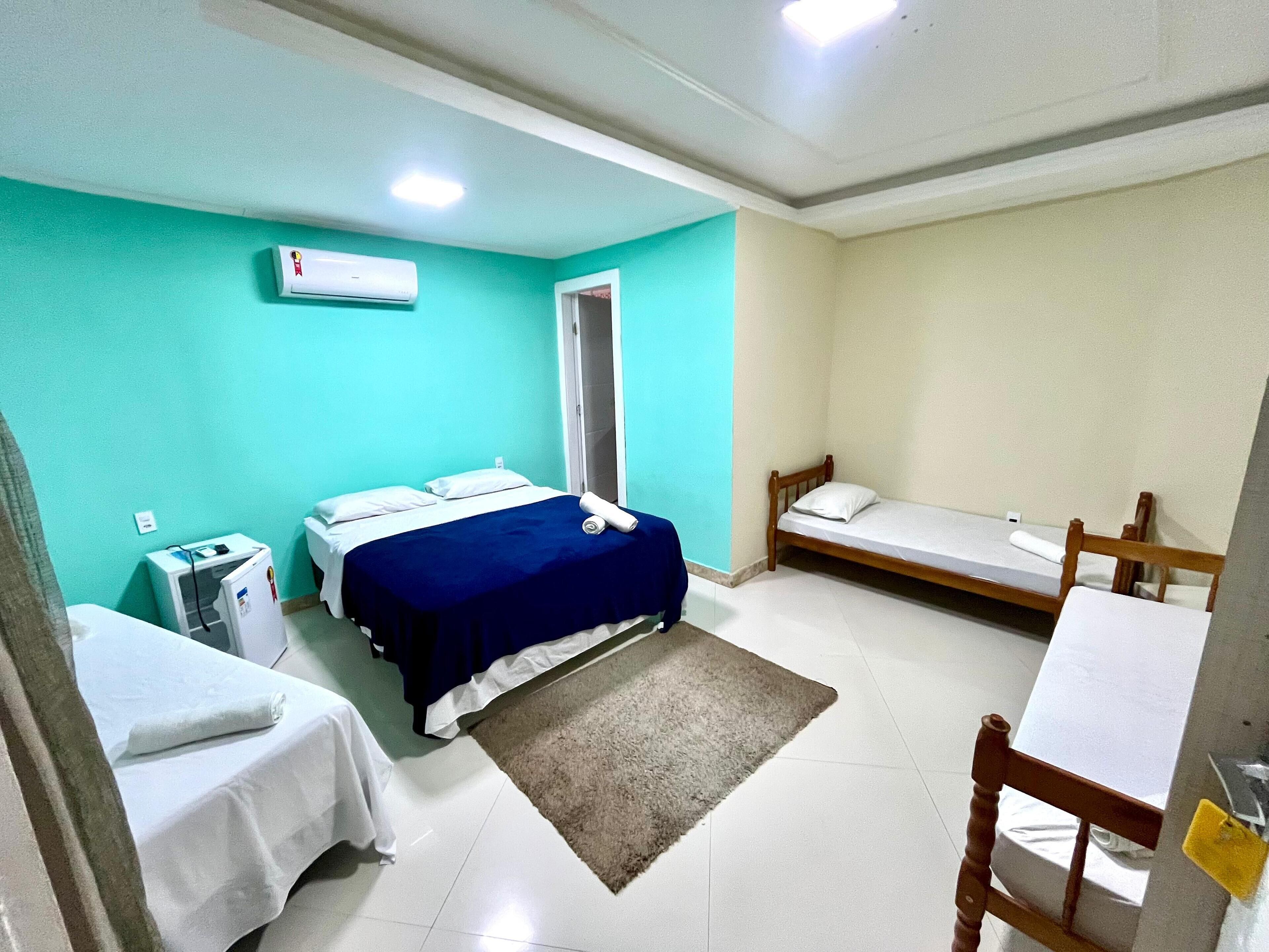 A small, clean room with two beds, a desk, and a chair.