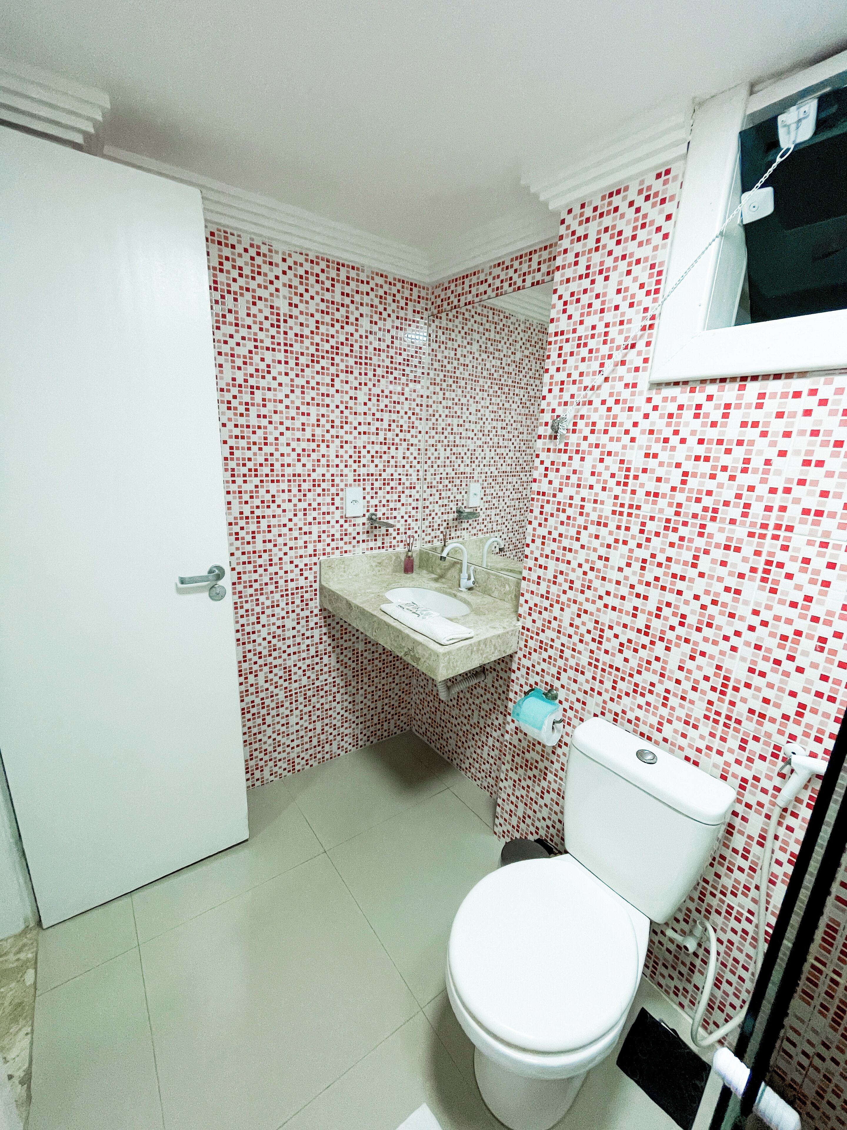 A bathroom with a white toilet, a sink with a mirror, and a tiled wall.