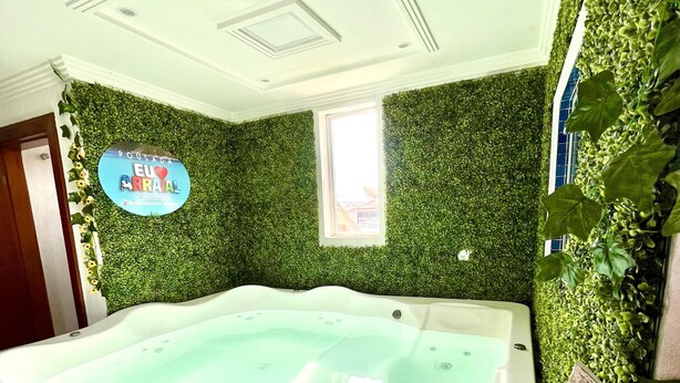 Een spa ruimte met een bubbelbad, een groene wand en een bord waarop staat 