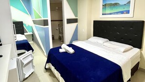 Een hotelkamer met een bed, een bureau en een badkamer die door een open deur zichtbaar is.