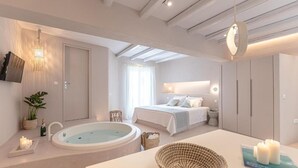 A modern bedroom with a large bed, a separate bathroom with a bathtub, and a skylight. - Supreme Suite with Spa Bath (Naxos)