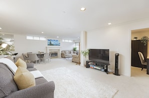 A modern living room with a flat-screen TV, a fireplace, a dining area, and a sofa.