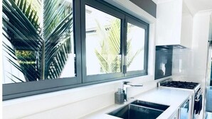 Een moderne keuken met een groot raam, witte aanrechtbladen en een roestvrijstalen fornuis.
