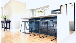 Een moderne keuken met een centraal eiland, barstoelen en een koelkast.