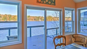 A room with large windows overlooking a body of water, a wooden deck, and wicker furniture. - Waterfront Cottage 10 Min From Great Barrington (New Marlborough)