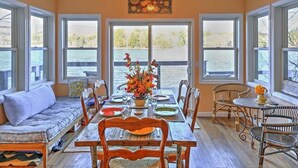 A dining room with a view of a lake, a sofa, and wicker chairs. - Waterfront Cottage 10 Min From Great Barrington (New Marlborough)
