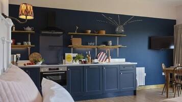 A modern kitchen with dark blue cabinets, a central island, and a variety of kitchenware and decorative items.