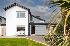 A modern two-story house with a front porch, a garage, and a well-maintained lawn.