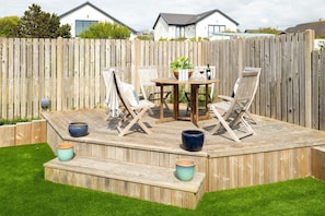 A wooden deck with a table and chairs, surrounded by a wooden fence.