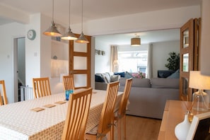 A dining area with a table, chairs, and pendant lights. - Cae Cloc: A pet-friendly cottage in Rhosneigr, Anglesey (Rhosneigr)
