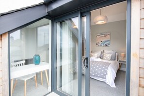 A room with a bed, a bedside table, a lamp, and a window with curtains.