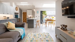Une cuisine moderne avec des meubles blancs, un îlot central et un coin repas comprenant une table et des chaises.