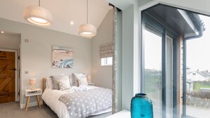 Une chambre à coucher avec un lit, des lampes de chevet, une grande fenêtre et un vase décoratif.