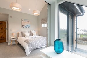 A bedroom with a bed, bedside tables, a window with a view, and a decorative vase. - Fronallt: A fabulous 3 bedroom property in Rhosneigr (Rhosneigr)