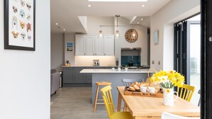 Une cuisine moderne avec des meubles gris, un îlot central et un coin repas avec des chaises jaunes.