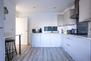 A modern kitchen with white cabinetry, a central island, and a bar stool.