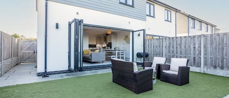 A residential property with a patio area, outdoor furniture, and a visible kitchen.
