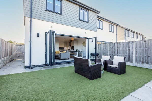 A residential property with a patio area, outdoor furniture, and a visible kitchen.