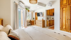 Un dormitorio moderno con una cama grande, un escritorio y una kitchenette.