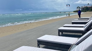 Un área de descanso frente a la playa con sillones de mimbre y una terraza de madera.