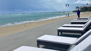 A beachside lounge area with wicker lounge chairs and a wooden deck. - Kite Beach Suite with Work Space and Full Kitchen (Cabarete)