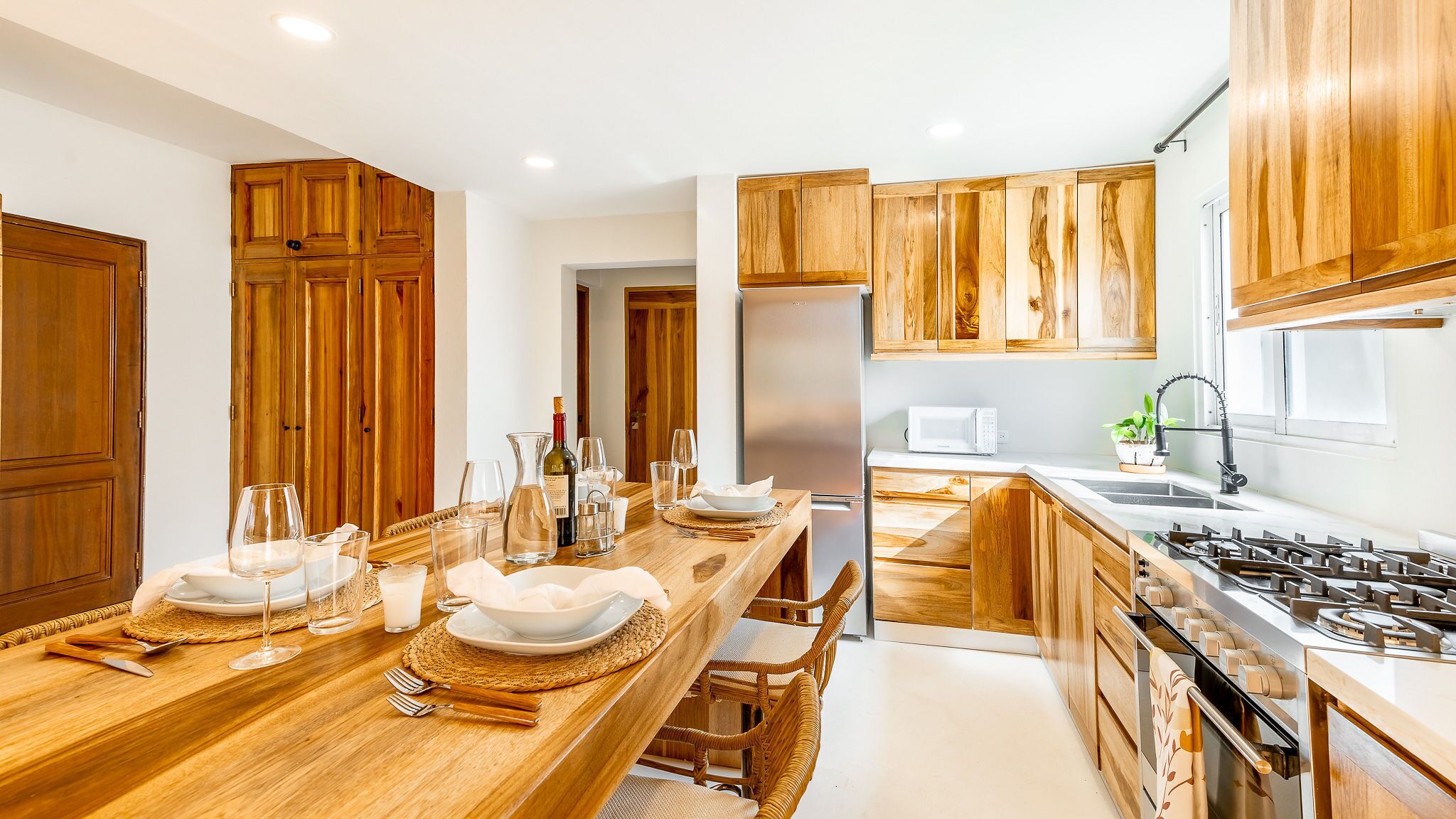 A modern kitchen with wooden cabinets, a stainless steel refrigerator, a microwave, and a gas stove.