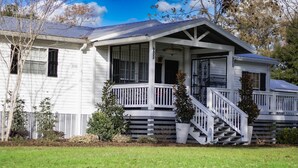 A white two-story house with a porch and a staircase leading to the second floor. - All You Ever Wanted "The White House" (Columbia County)