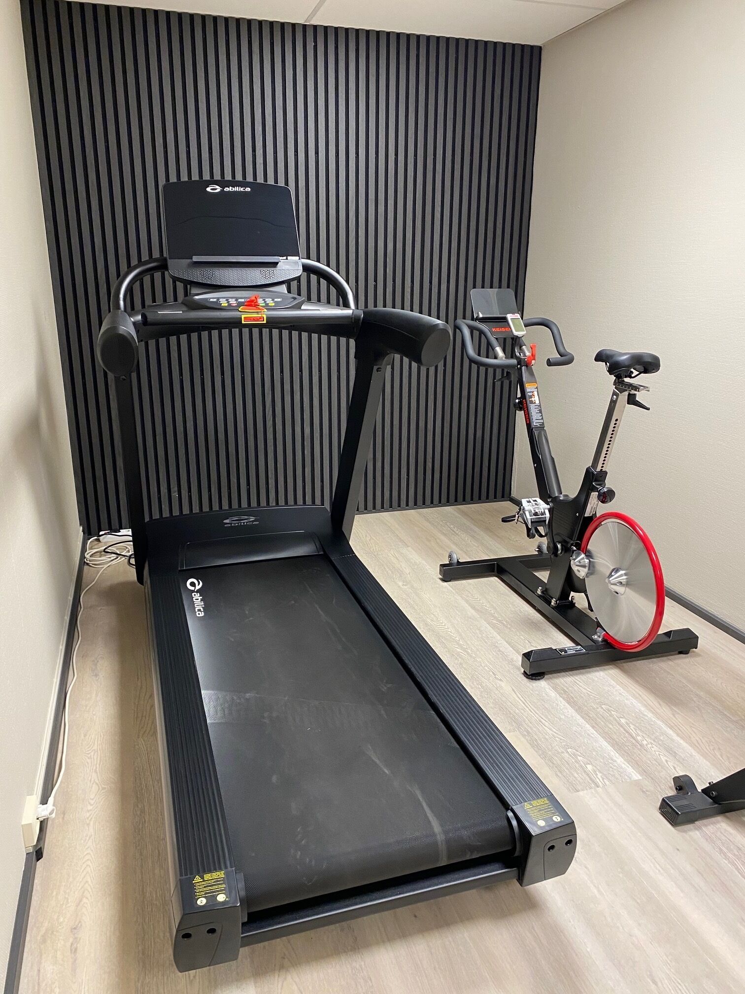 A room with a treadmill and a stationary bike.