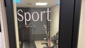 A gym entrance with a sign reading "Sport" and exercise equipment visible through the glass door. - Marina Hotel Sortland (Sortland)
