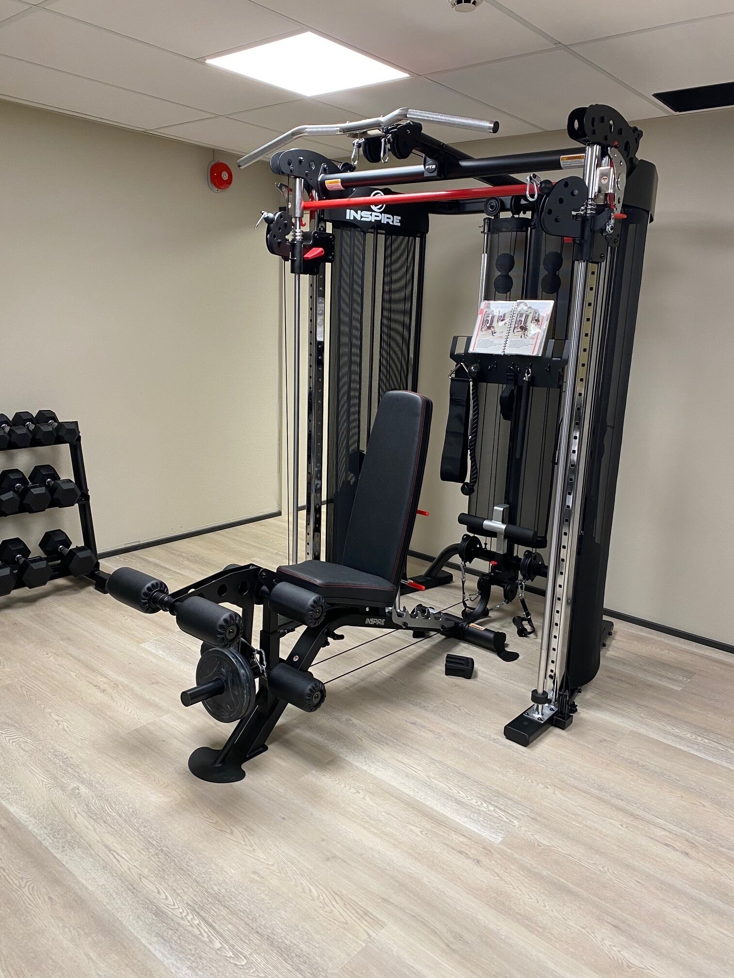 A gym with a bench press, dumbbells, and a squat rack.