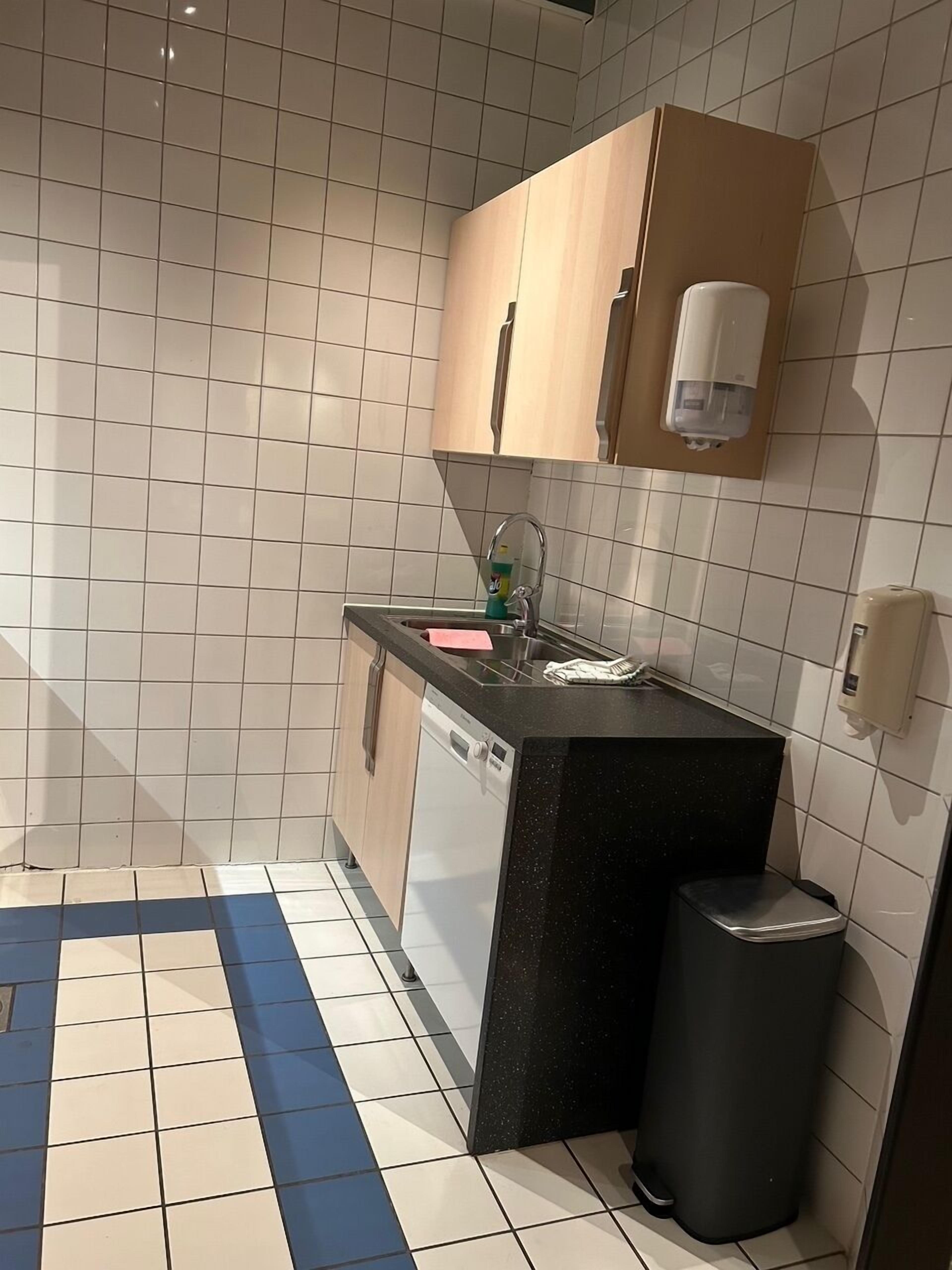 Cocina compacta con lavaplatos, fregadero y basurero.