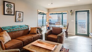 Una sala de estar con un sofá de cuero marrón, una mesa de centro de madera y vistas a un balcón con mesa y sillas.