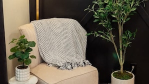 Ein gemütlicher Sitzbereich mit gepolstertem Sessel, einem kleinen Beistelltisch mit Pflanze und einer stehenden Stehlampe.