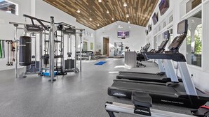 Une salle de sport équipée de machines de cardio, de bancs de musculation et dotée d’un plafond en bois.