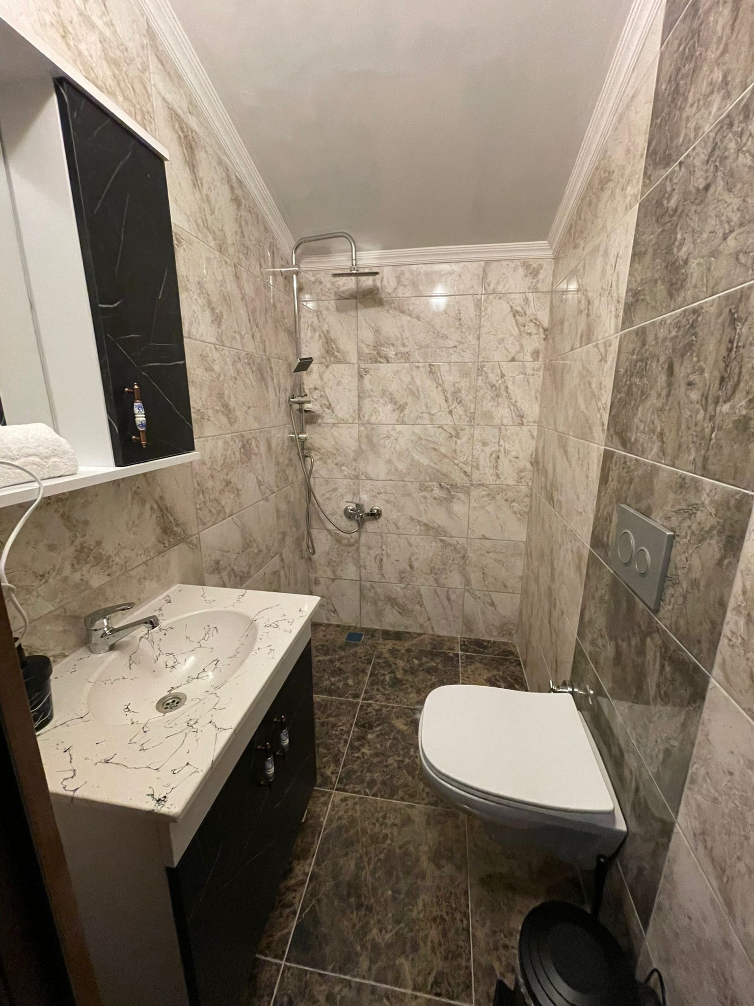 A bathroom with a marble sink, a toilet, and a shower.