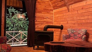 A cozy room with a wooden interior, a fireplace, a balcony with a view, and a patterned sofa. - Bizim O'ra Küme Evleri & Bungalov (Maçka)