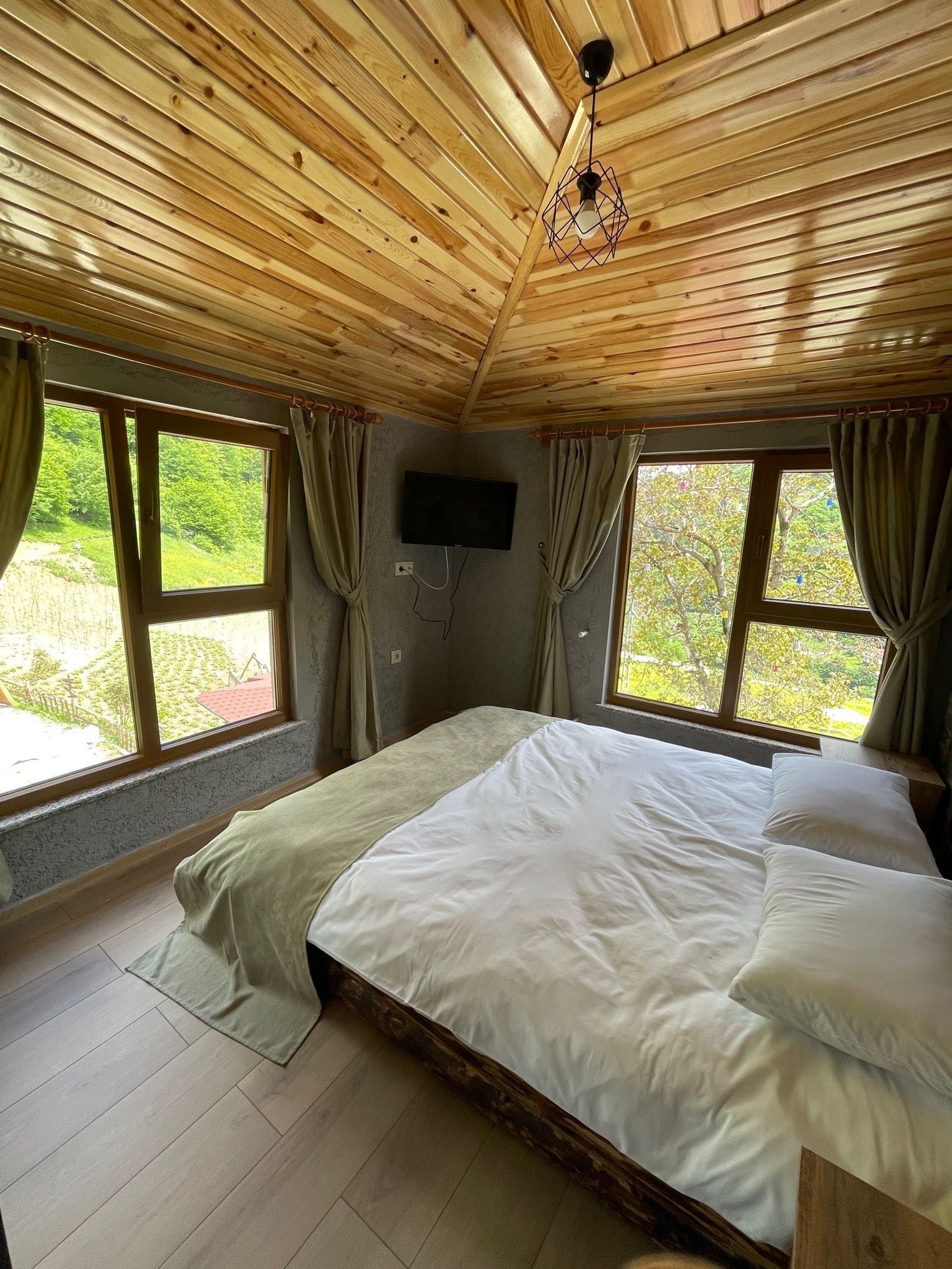 Una habitación con paneles de madera, una cama, ventanas amplias y un televisor de pantalla plana.