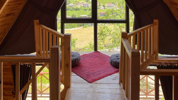 A wooden attic room with a large window offering a view of a green landscape. - Bizim O'ra Küme Evleri & Bungalov (Maçka)