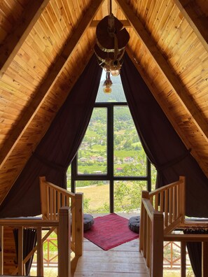A wooden attic room with a large window offering a view of a green landscape. - Bizim O'ra Küme Evleri & Bungalov (Maçka)