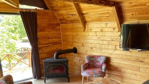 A cozy wooden cabin interior with a sofa, patterned armchair, and a red rug. - Bizim O'ra Küme Evleri & Bungalov (Maçka)