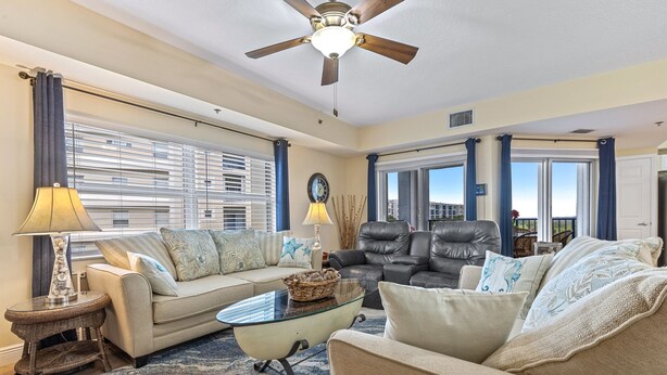 A living room with a ceiling fan, two sofas, a glass coffee table, and a lamp.