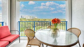 A balcony with a glass table, wicker chairs, and a red sofa.
