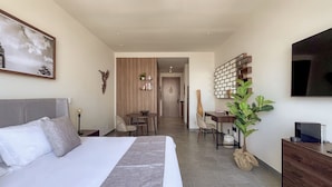 A modern hotel room with a large bed, a desk, a chair, a TV, and a plant. - Mi Zona Lodging Reforma (Mexico City)